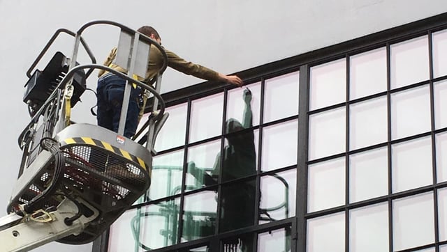 st-cloud-window-installer-on-a-lift-placing-a-glass-panel-into-a-large-black-framed-curtain-wall-window-system